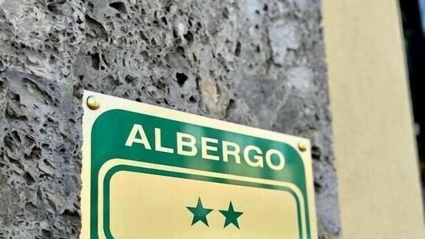 A sign for Albergo Hotel mounted on a textured wall. - Milan Hostel (Milan)
