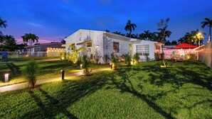 Una casa moderna con un prato curato, un vialetto e un ombrello rosso.
