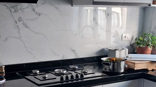 Una cocina moderna con encimera negra, armarios blancos y estufa de acero inoxidable.
