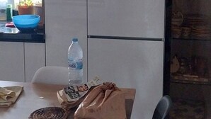 Una cocina moderna con un refrigerador blanco, una mesa de comedor con sillas y una botella de agua sobre la mesa.