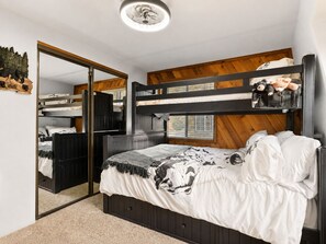 A bunk bed room with a wooden headboard, a mirror, and a small window. - Birdhouse in Moonridge (Big Bear City)