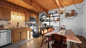 Una cocina con armarios de madera, lavavajillas de acero inoxidable, horno empotrado y una mesa de comedor con sillas.