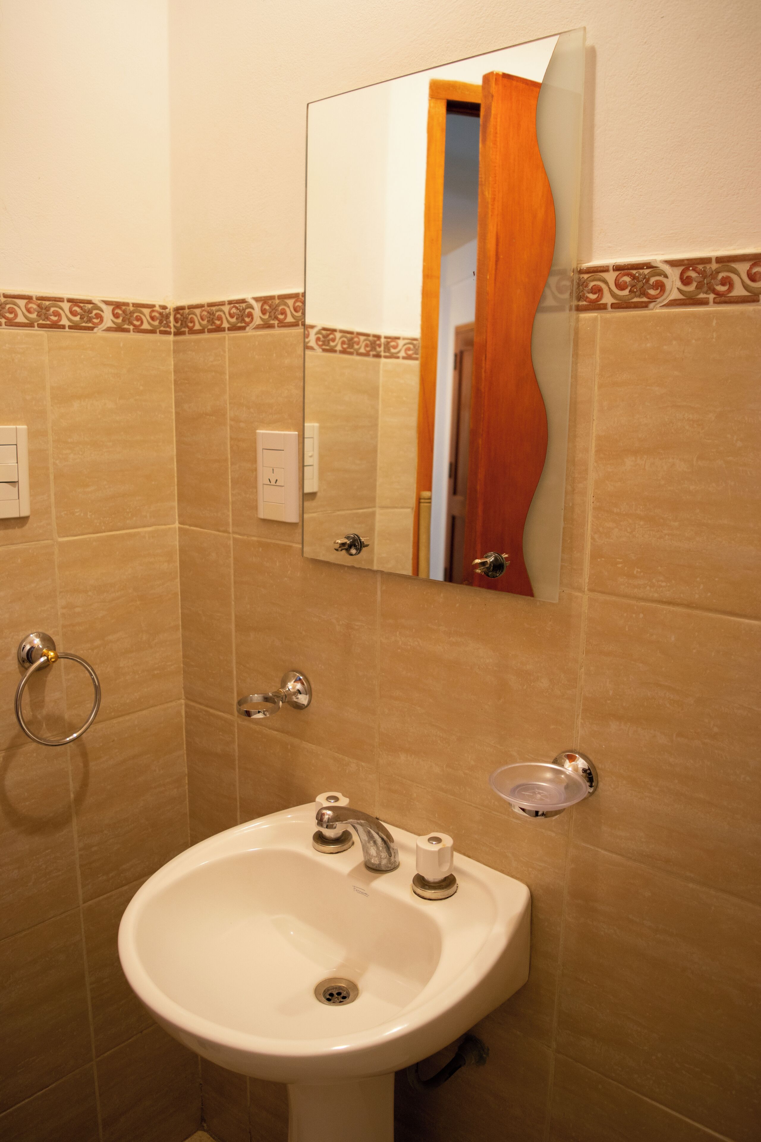 A bathroom with a sink, mirror, and towel ring.