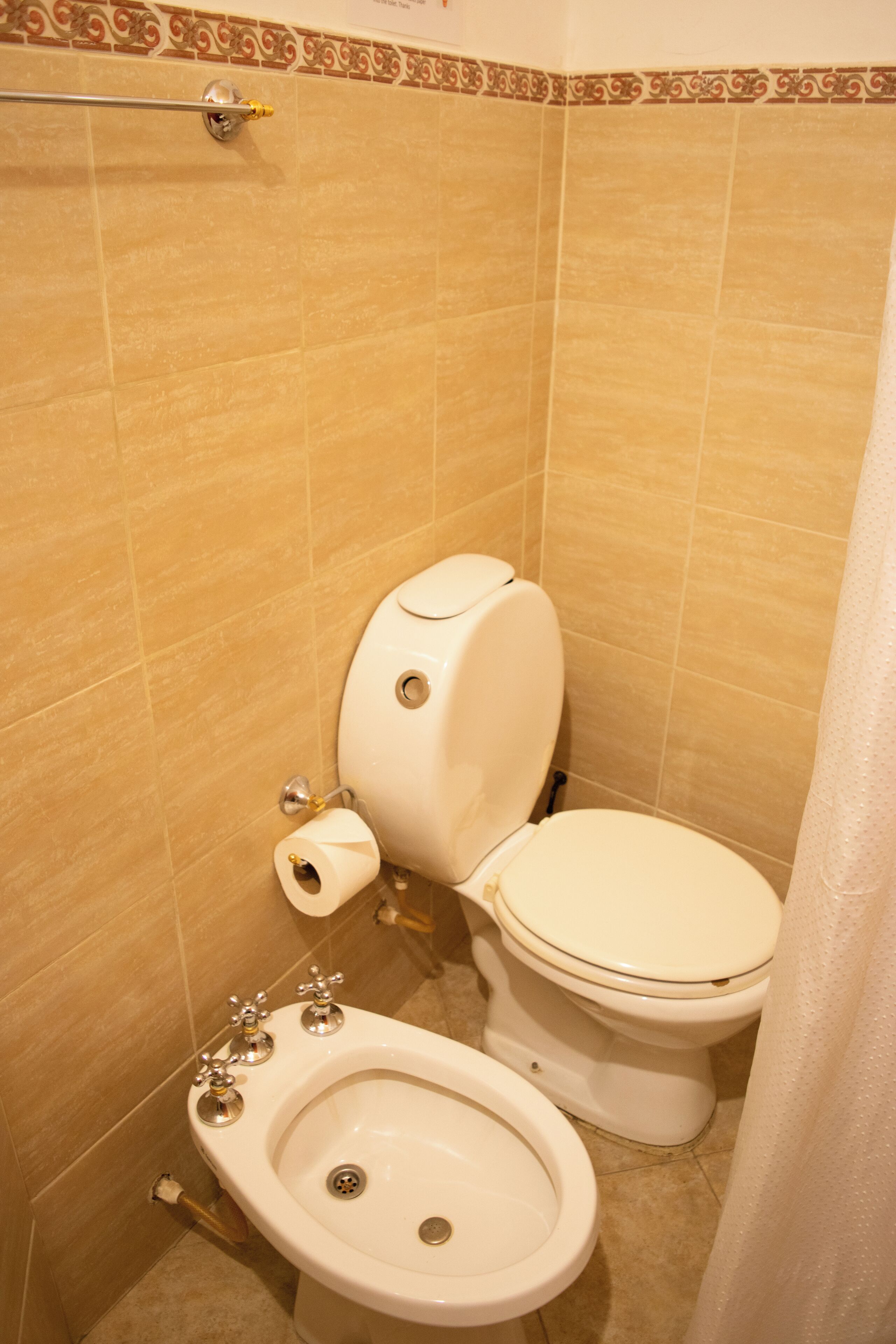 Un baño con inodoro, bidé y toallero.
