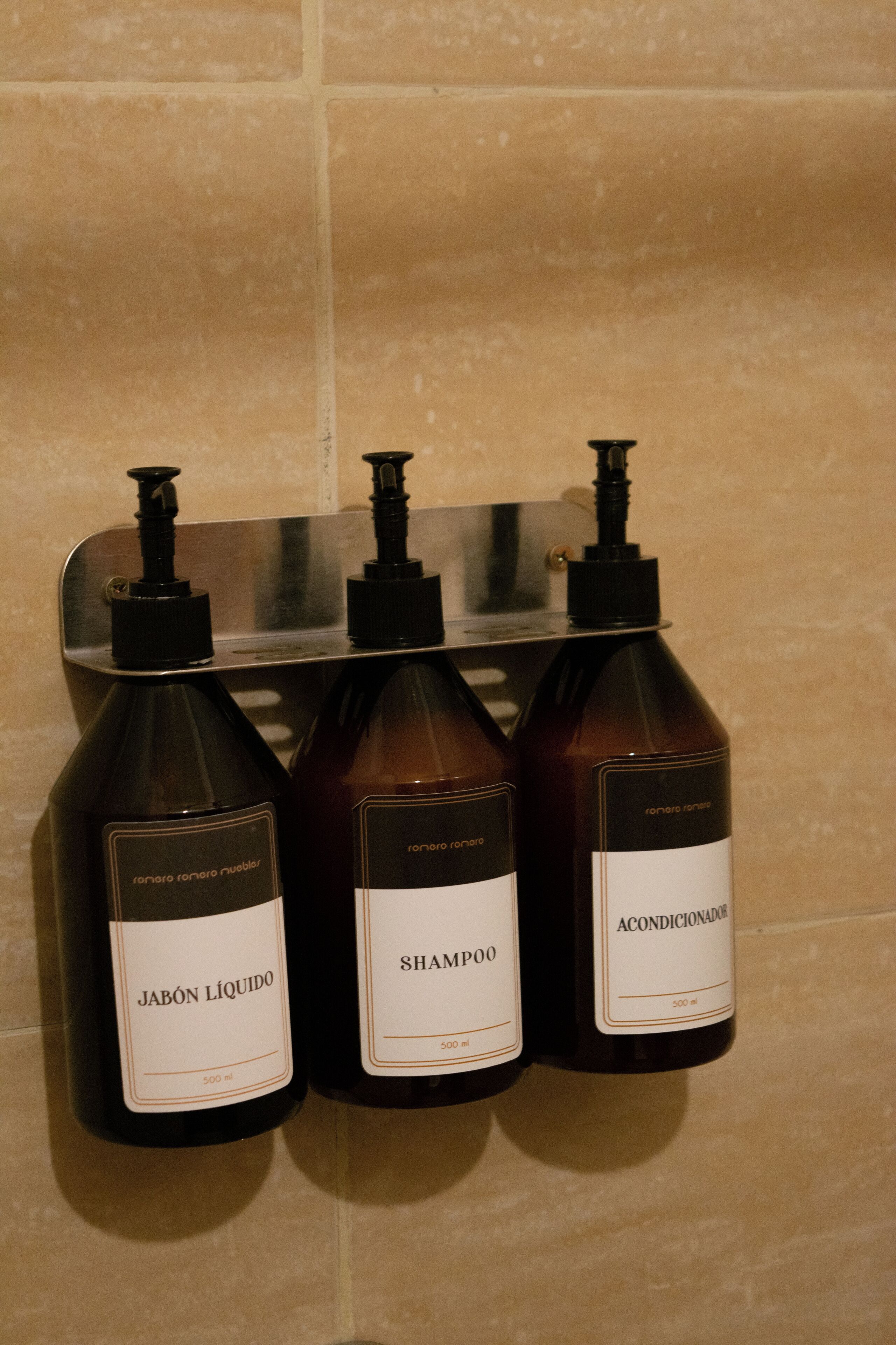 Tres botellas de productos Ronaro Ronaro en un dispensador montado en la pared.