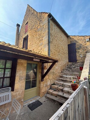 Un bâtiment en pierre avec un escalier en bois menant à une porte sur laquelle on peut lire : « La Dolce Vita ».