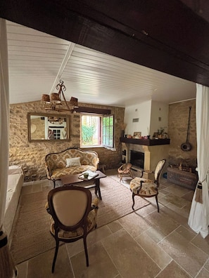 A rustic room with stone walls, a fireplace, a sofa, and a table.