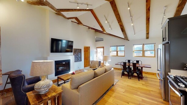 A spacious living area with a fireplace, sofa, dining table, and kitchen area.