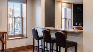 Una cocina moderna con un ventanal grande, una barra con taburetes y un salpicadero negro.