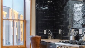 Una cocina con un ventanal grande, una estufa y una silla.