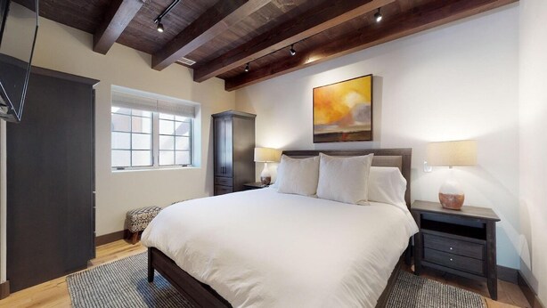 A bedroom with a large bed, two bedside tables, a wardrobe, and a window.
