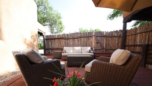 An outdoor patio with wicker furniture, a white sofa, and a wooden fence.