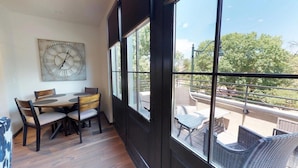 A room with a dining table and chairs, a large window with a view of the outdoors, and a wall-mounted clock. - The Lincoln 302, 1 Bed / 1 Bath, Luxury Condo (Santa Fe)
