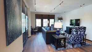 A modern living room with a sofa, a coffee table, a TV, and a patterned chair. - The Lincoln 302, 1 Bed / 1 Bath, Luxury Condo (Santa Fe)