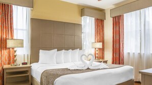 Ein Hotelzimmer mit einem großen Bett, zwei Nachttischen, einem Deckenventilator und Blick ins Freie durch Vorhänge.