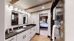 A modern bathroom with a large mirror, a sink, and a shower area.