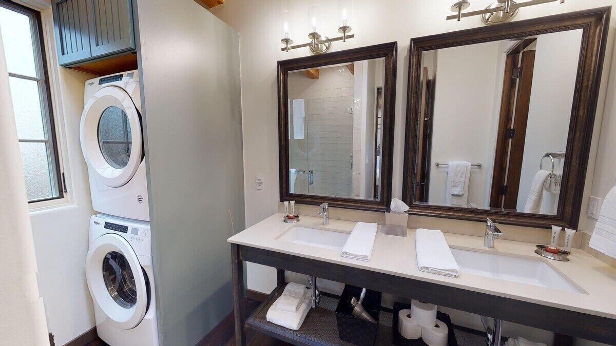 A bathroom with a washing machine, two sinks, and two large mirrors.