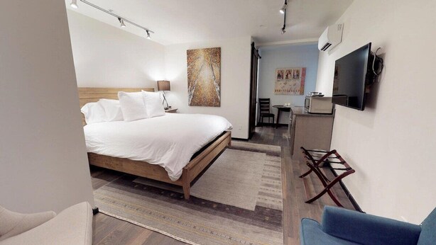 Ein Hotelzimmer mit einem Bett, einem Schreibtisch, einem Stuhl, einem Fernseher und Bildern an der Wand.