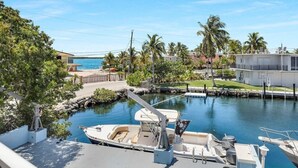 A marina with boats docked, a clear blue sky, and a view of a beach and buildings in the background. - Large  Ocean Front, Loft House with 3 beds, 2 baths in Key Largo with Boat Dock (Key Largo)
