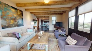 A spacious living room with a high ceiling, a large abstract painting, and a view of the outdoors through large windows. - The Lincoln 402, 2 Bed / 2.5 Bath, Luxury Condo (Santa Fe)