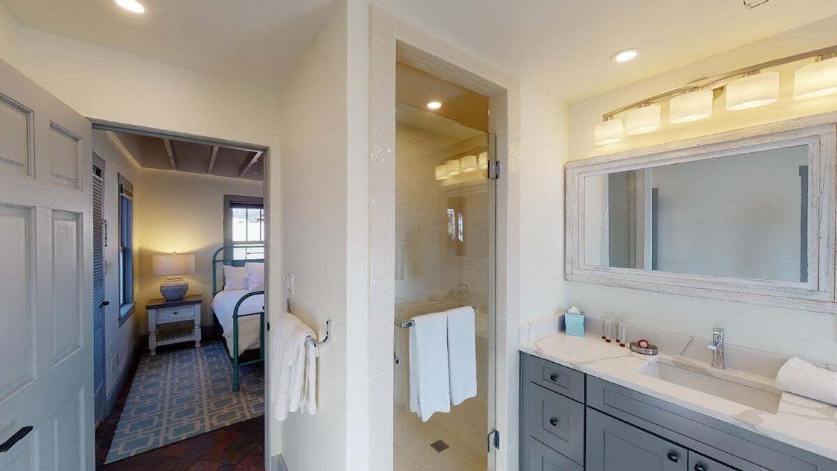 A bathroom with a large mirror, a sink, and a shower area.