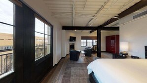 Une chambre d’hôtel avec un grand lit, un bureau, une chaise, une télévision et une fenêtre donnant sur des immeubles.