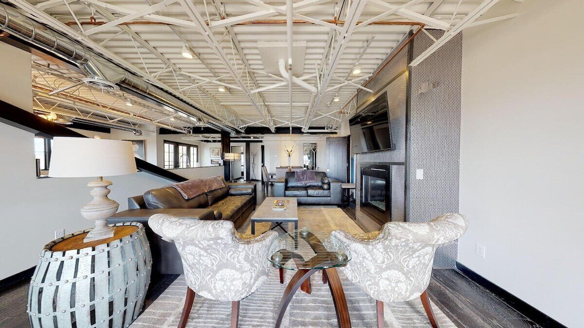 A spacious living area with a high ceiling, a fireplace, and a seating arrangement.