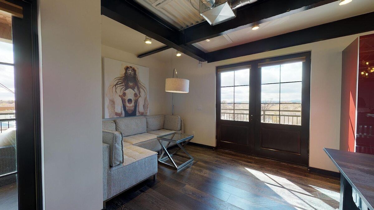 Een moderne woonkamer met een bank, een schilderij, een raam en een deur.