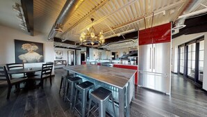 Une cuisine spacieuse avec un grand îlot central, des tabourets de bar et un lustre.