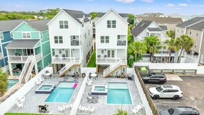 A residential complex with multiple two-story houses, a swimming pool area with lounge chairs, and a parking lot.