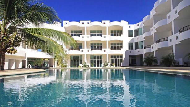 Una piscina con un edificio blanco al fondo.