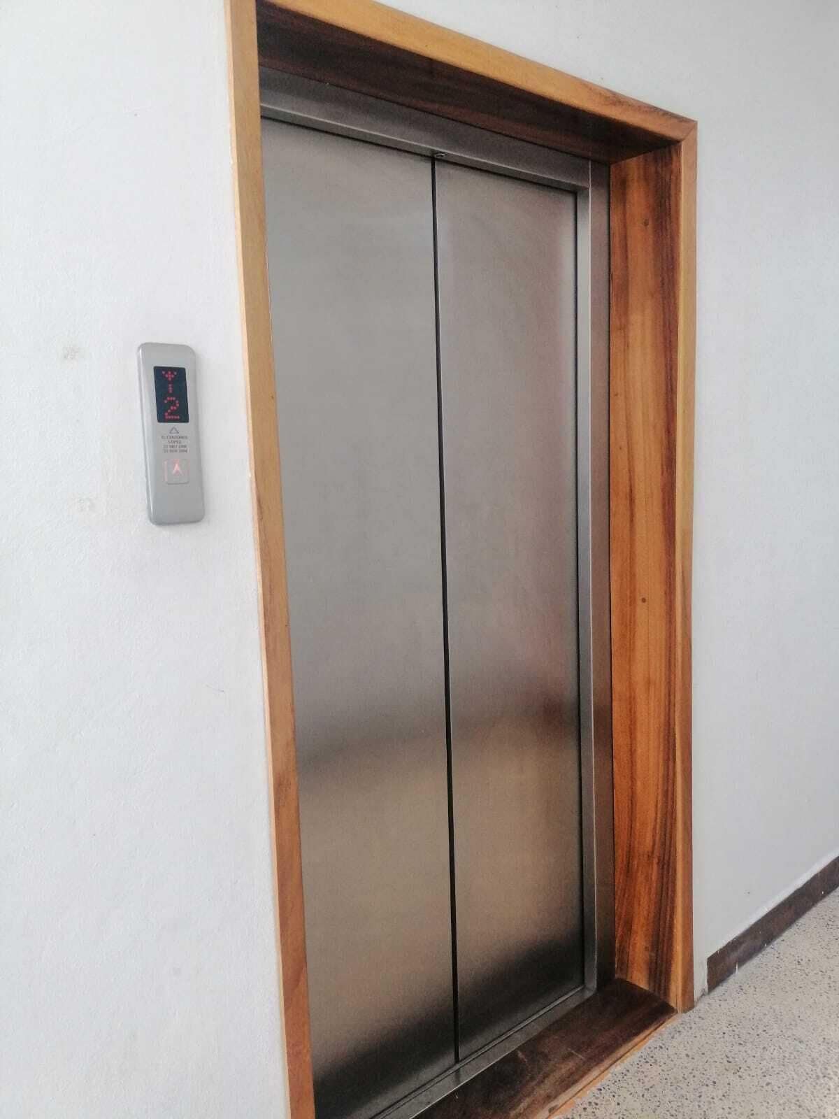 A modern elevator with a metallic finish and a wooden frame.