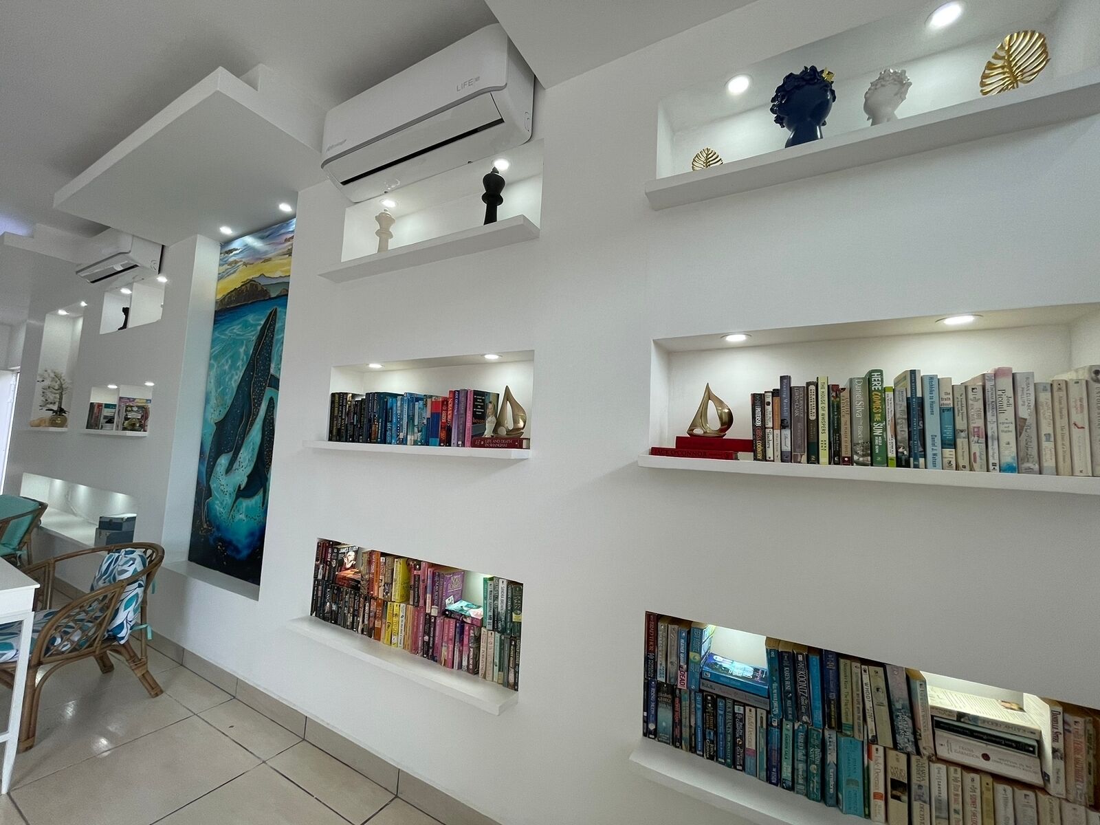 Een modern interieur met witte muren, meerdere boekenkasten en een groot abstract schilderij.