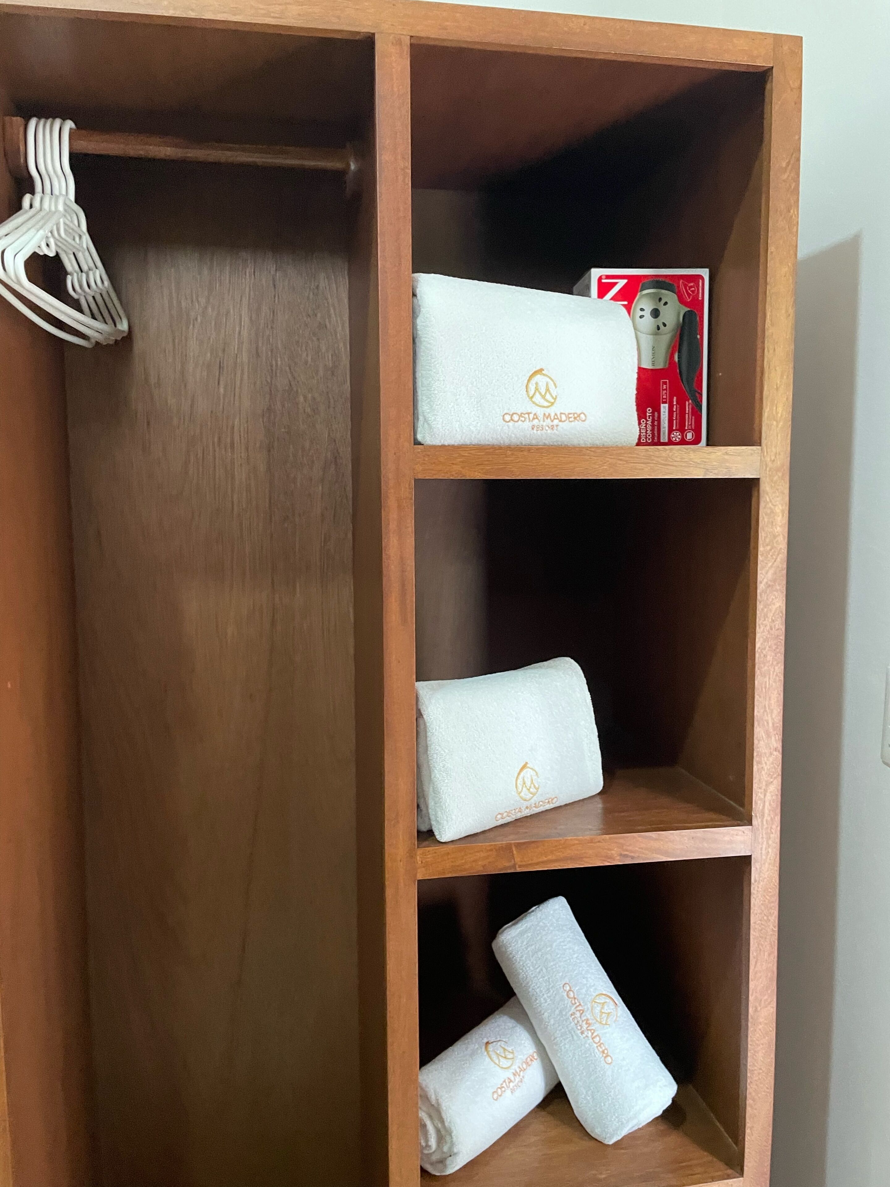 Une étagère en bois avec trois serviettes blanches et une boîte rouge contenant une serviette blanche.