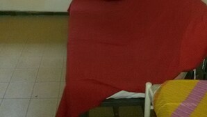 Una habitación con una silla roja, una silla azul y una pared con una pizarra blanca.