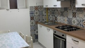 Una cocina compacta con armarios blancos, estufa a gas, horno y salpicadero con diseño.