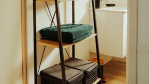 Ein Zimmer mit einer schwarzen Metallregaleinheit an der Wand, die gefaltete Handtücher und einen gewebten Korb enthält.