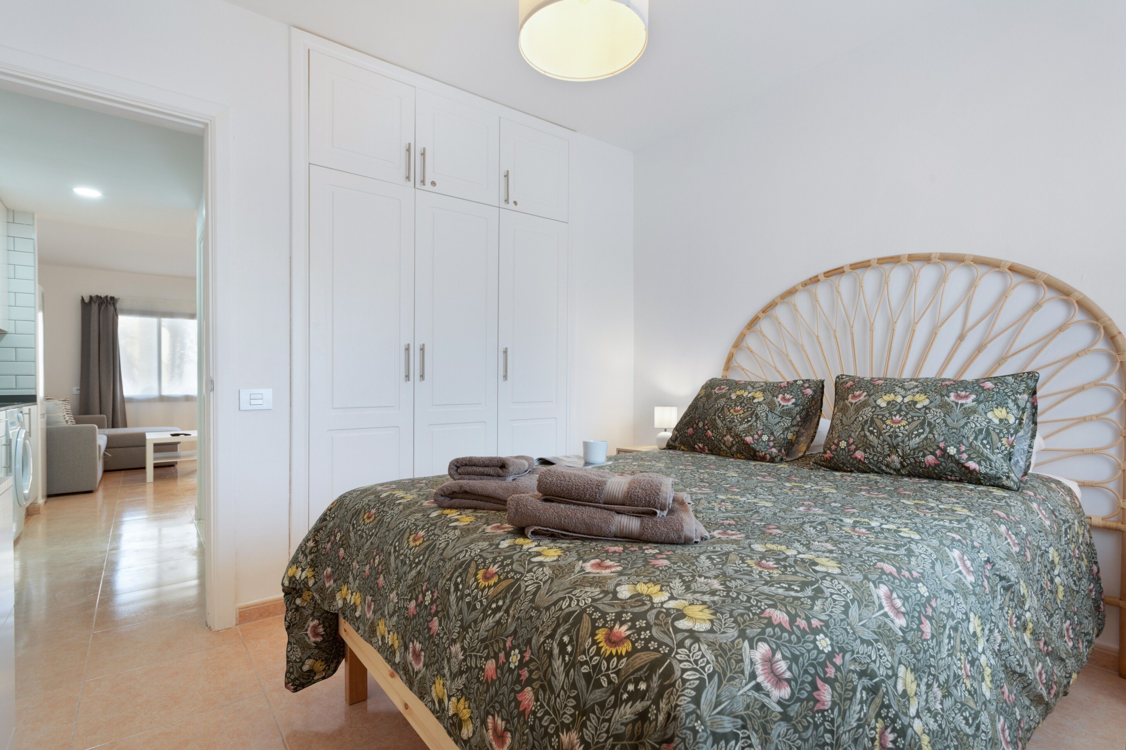 A bedroom with a bed, a wardrobe, a bedside table, and a lamp.
