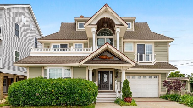 A two-story house with a front porch, a garage, and a well-maintained lawn. - Charming newly updated home in Avalon with endless views of bay and sunset (Avalon)