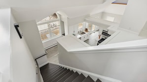 A modern interior with a staircase leading to a kitchen area. - Charming newly updated home in Avalon with endless views of bay and sunset (Avalon)