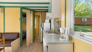A compact kitchen with a gas stove, coffee maker, and a window overlooking a brick wall.