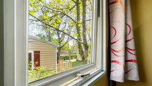 A window with a view of a house, a curtain, and a window handle.