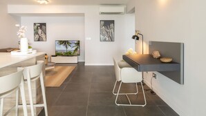 A modern kitchen with a dining area, a flat-screen TV, and a small island with a vase of flowers. - Florida Soleil luxury and sea view (Schoelcher)