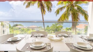 A dining table set for four with a view of the ocean and palm trees. - Florida Soleil luxury and sea view (Schoelcher)