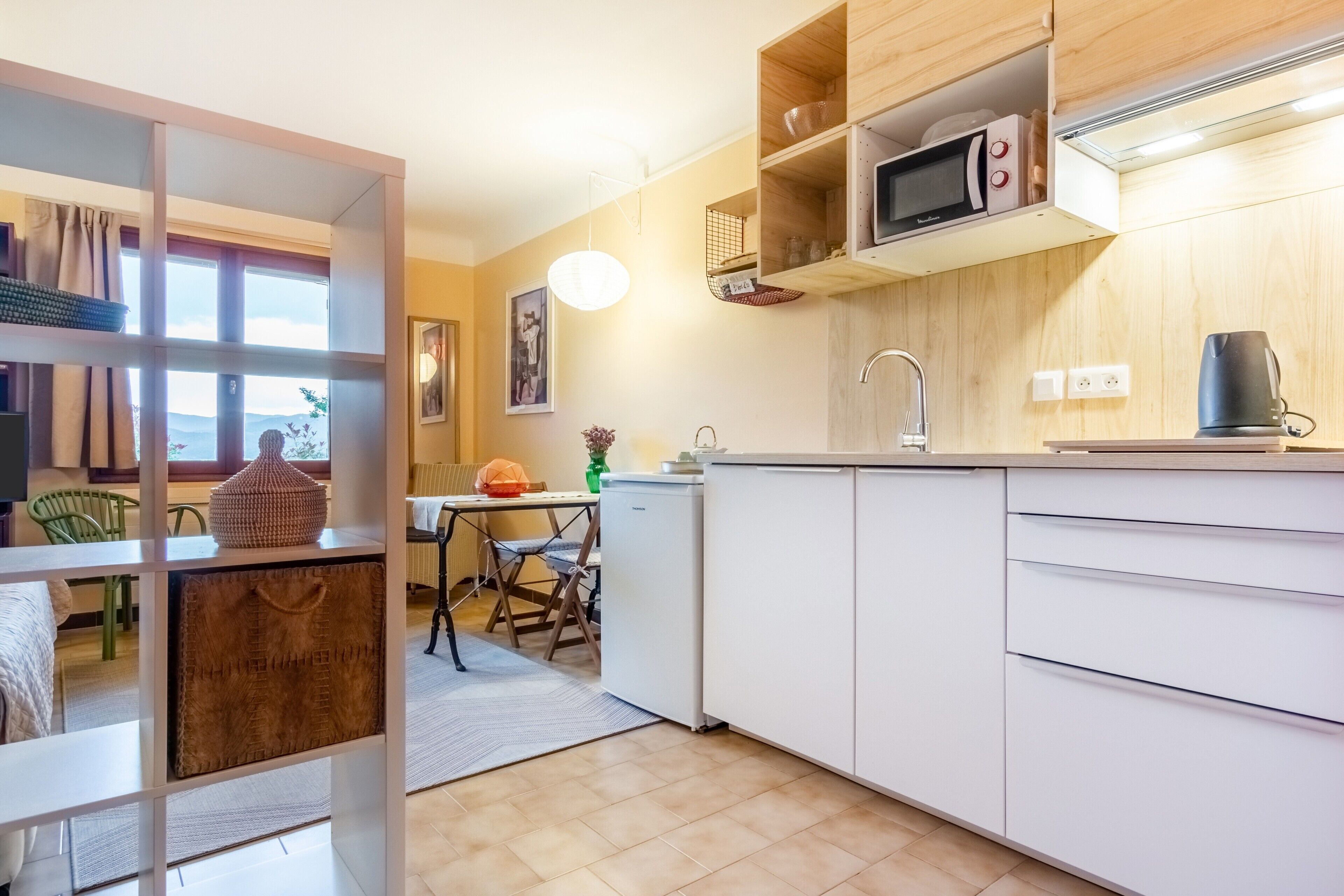 A modern kitchen with white cabinets, a microwave, and a coffee maker.