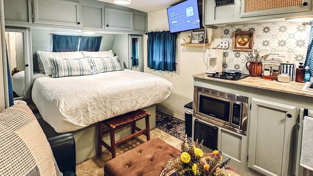 A compact RV interior with a bed, kitchenette, and seating area. - Starlight Retreat RV in Springtown with AC, WiFi (Springtown)
