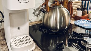 A kitchen with a Cuisinart coffee maker, a stainless steel kettle, and a stove. - Starlight Retreat RV in Springtown with AC, WiFi (Springtown)