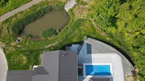 Una casa moderna con piscina, amplio camino de entrada y estanque.