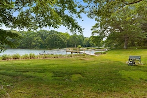 Un parc avec un pont en bois enjambant un lac, un banc et une végétation luxuriante.