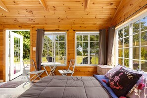 Una habitación de cabaña de madera con una cama, una mesa y sillas.